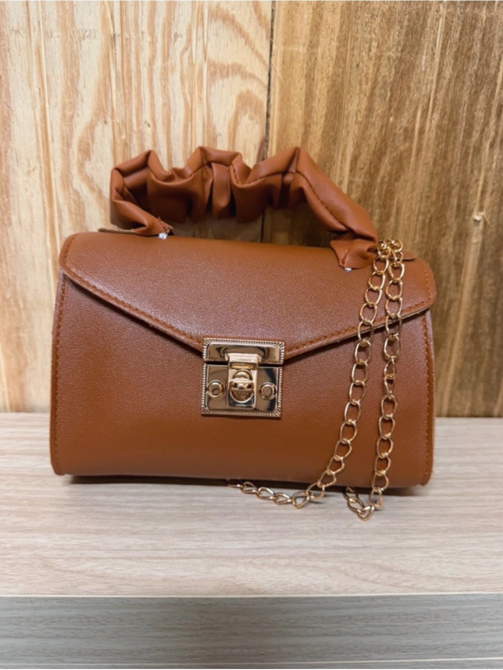 Brown ruched drawstring crossbody bag with gold chain